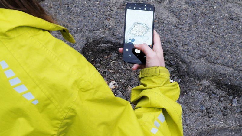Somebody taking a photo of a pothole.